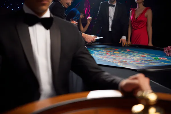 A professional dealer in a tuxedo greeting players at the roulette table, symbolizing the authentic live casino feel at BIGPARI.
